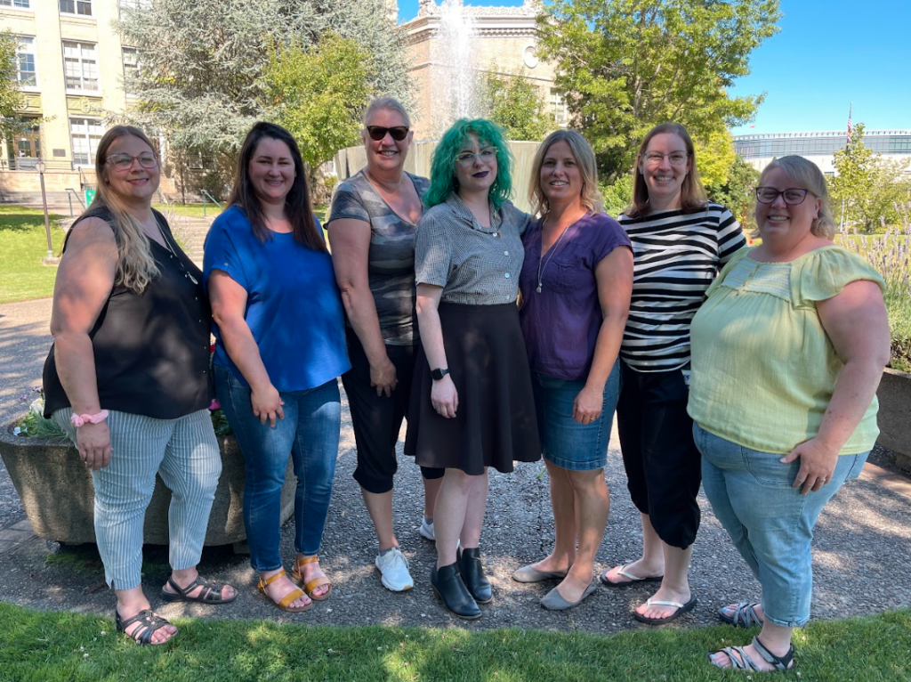 A photo of the seven members of the 2023-2024 Oregon CUPA-HR board. They are standing in front of a fountain smiling and facing the camera.